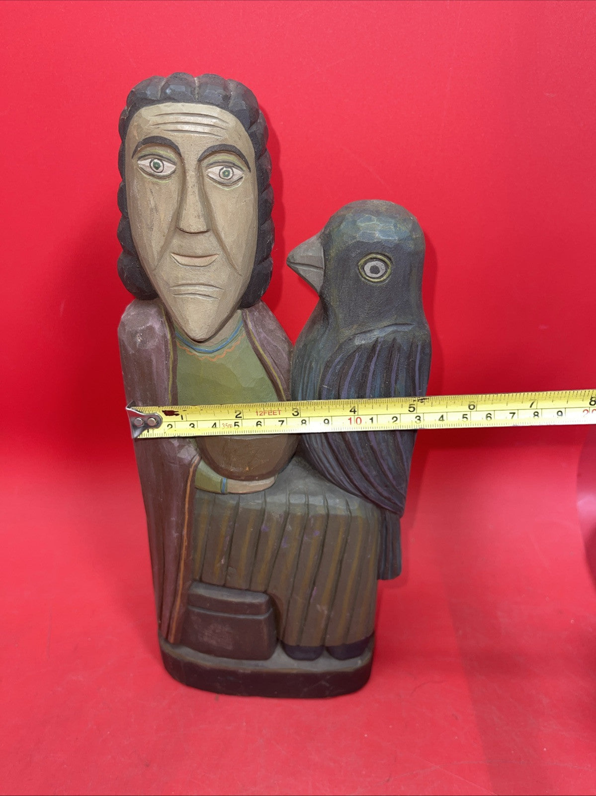 Vintage An ancient folk wood carving depicting a seated figure with a bird.