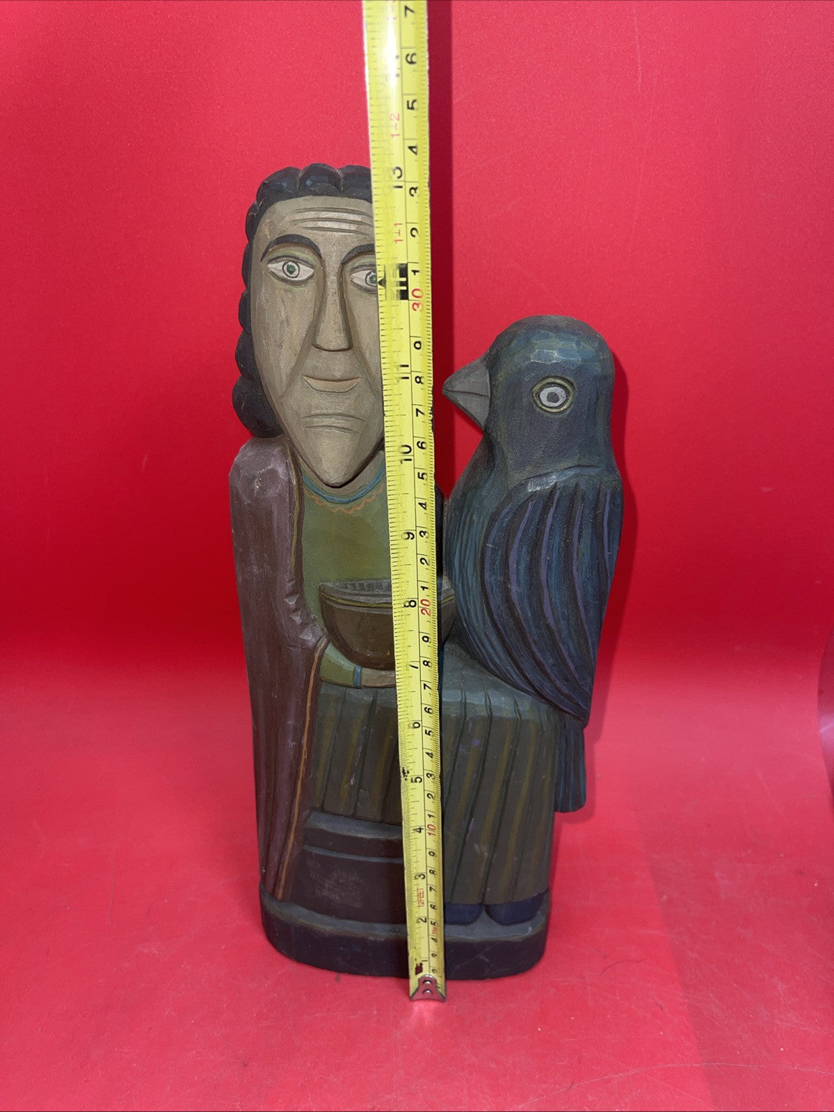 Vintage An ancient folk wood carving depicting a seated figure with a bird.