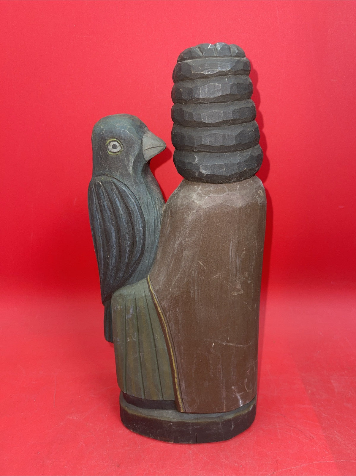 Vintage An ancient folk wood carving depicting a seated figure with a bird.