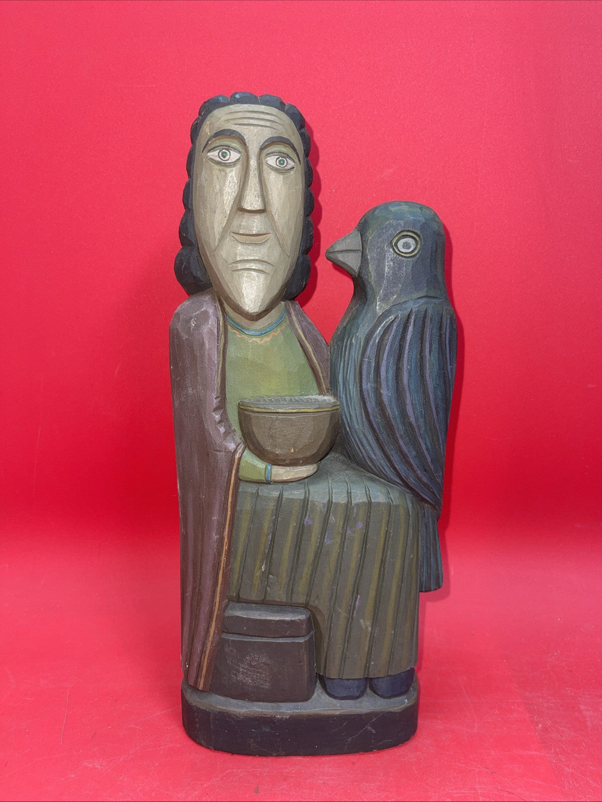 Vintage An ancient folk wood carving depicting a seated figure with a bird.