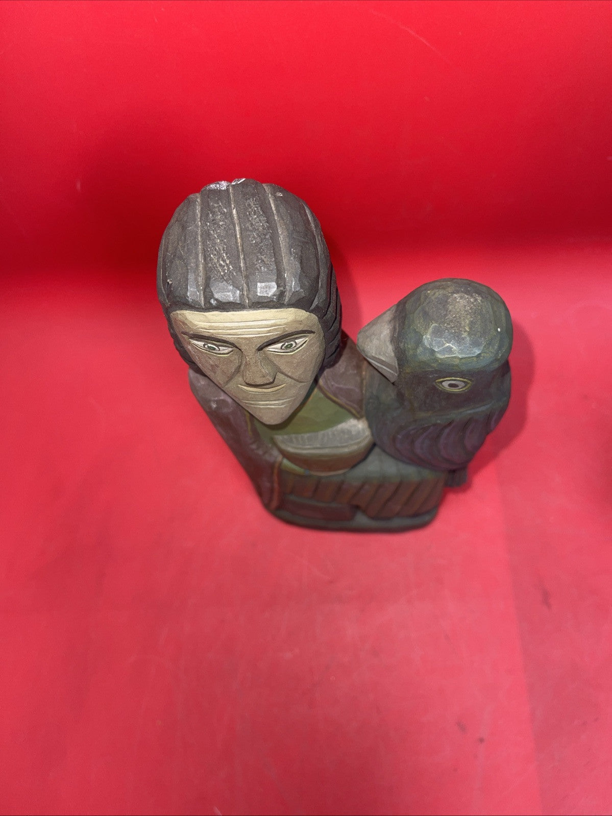Vintage An ancient folk wood carving depicting a seated figure with a bird.