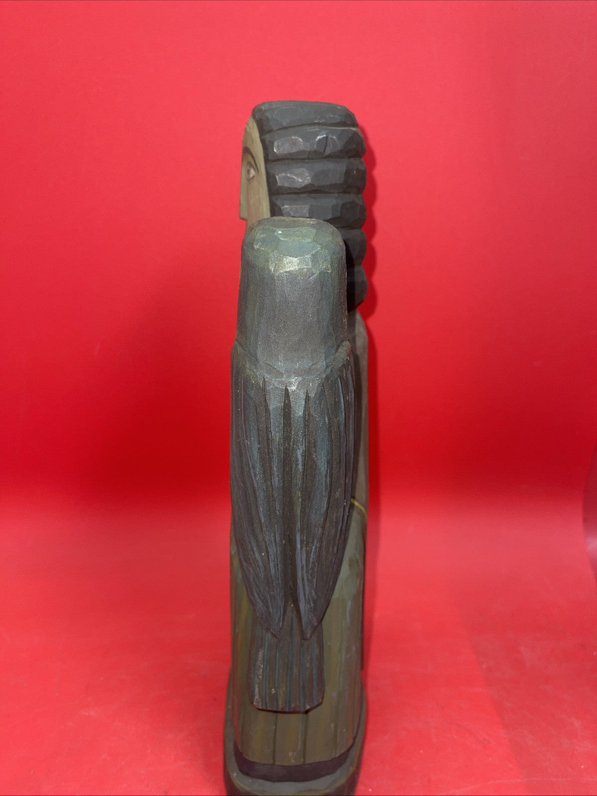 Vintage An ancient folk wood carving depicting a seated figure with a bird.